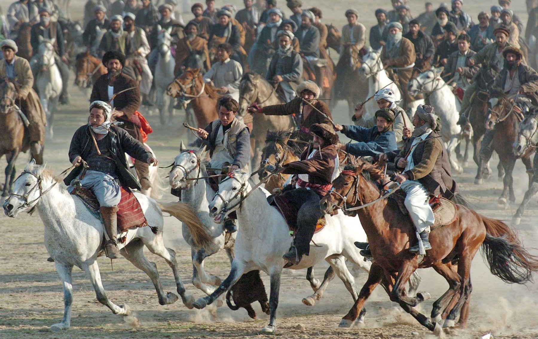 Afghan horsemen chase the player who grabbed the goat during the traditional Buzkashi game in Kundus, Afghanistan. The carcass of an animal, preferably goats, is being prepared 24 hours before the game so it remain intact and not be torn to pieces as hundreds of horsemen independently compete to grab and carry the carcass to the winning circle. To begin the game, a pit is dug and the carcass is placed into it so that the top of the carcass is level with the ground. A large circle is drawn around the pit. The horsemen encircle the pit containing the carcass, and on a given signal, compete to grab it and gallop away around one post and then the other before returning and throwing the boz back into the pit. The other riders try to prevent that by attacking the rider and trying to steal the carcass away. The horseman who returns the carcass into the pit is considered the winner. Photo by Boris Roessler/dpa