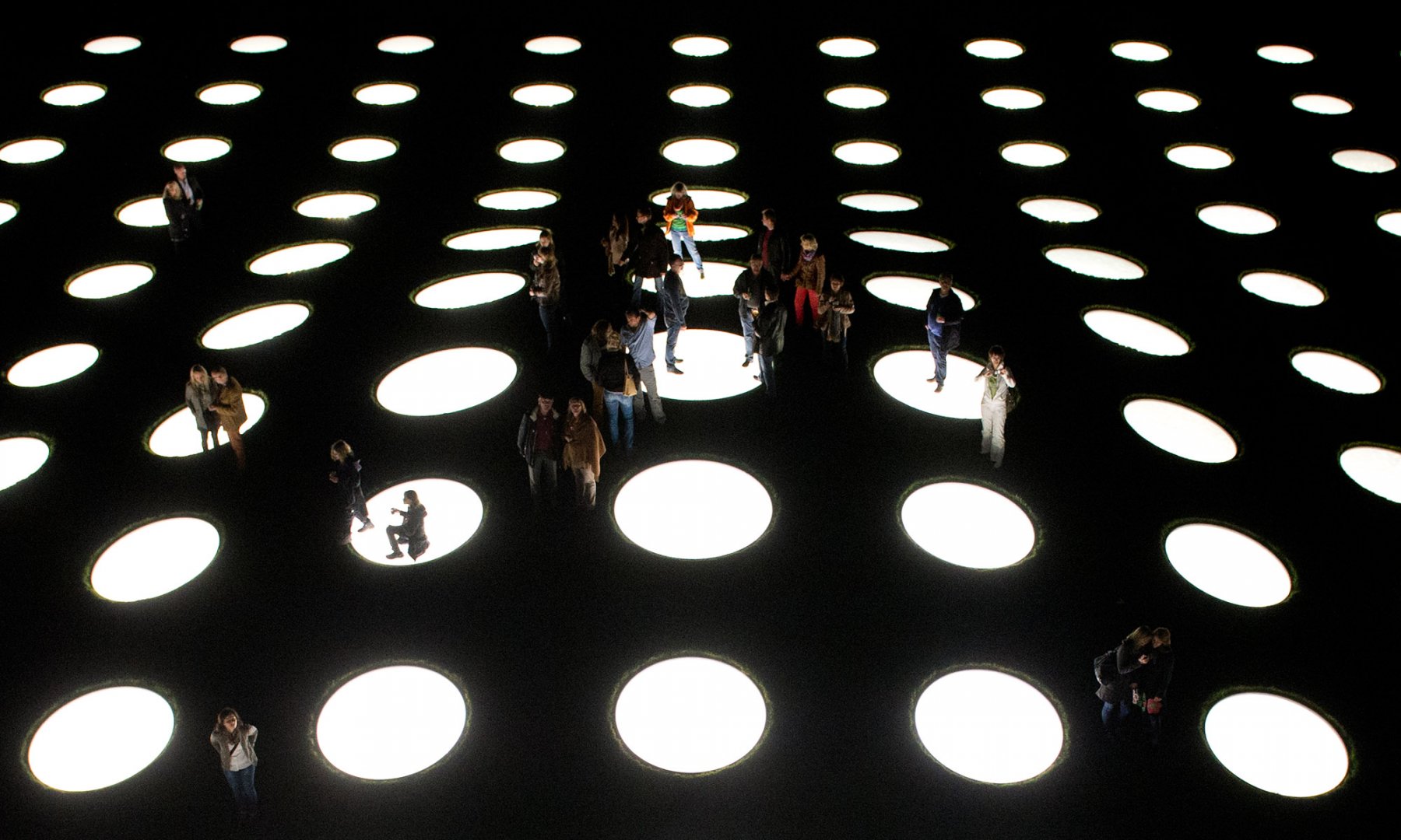 Silhouettenhaft zu erkennen sind Besucher, die nachts auf den erleuchteten Oberlichtern des Museums "Städel" in Frankfurt am Main stehen. Foto: Boris Roessler/dpa