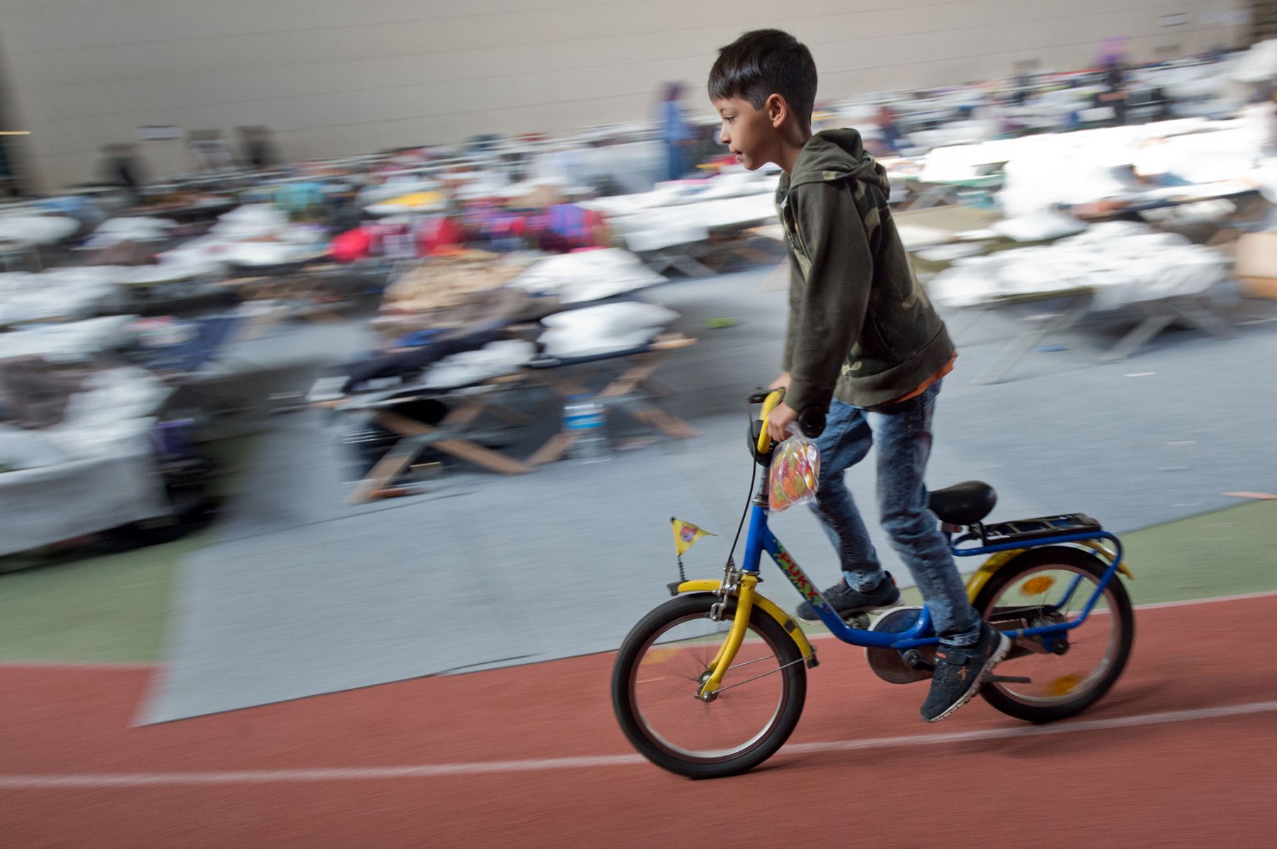 Mit einem geschenkten Fahrrad flitzt dieser Junge in der August Schärttner Turnhalle in Hanau an Feldbetten vorbei. Foto: Boris Roessler/dpa 