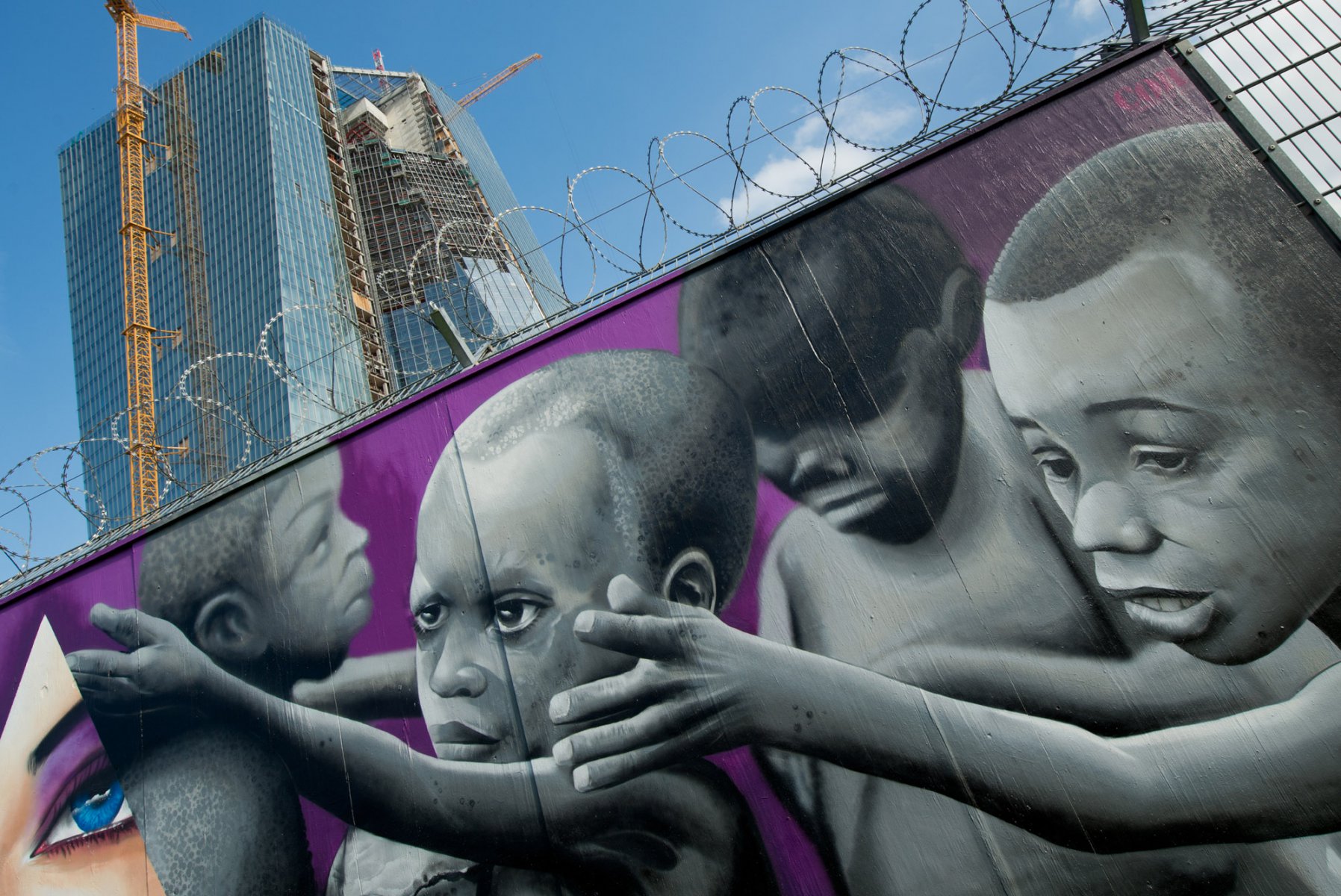 Hungernde und kranke afrikanische Kinder zeigt ein Graffiti an dem Bauzaun des Neubaus der Europäischen Zentralbank (EZB) in Frankfurt am Main am 03.09.2013.  Foto: Boris Roessler/dpa