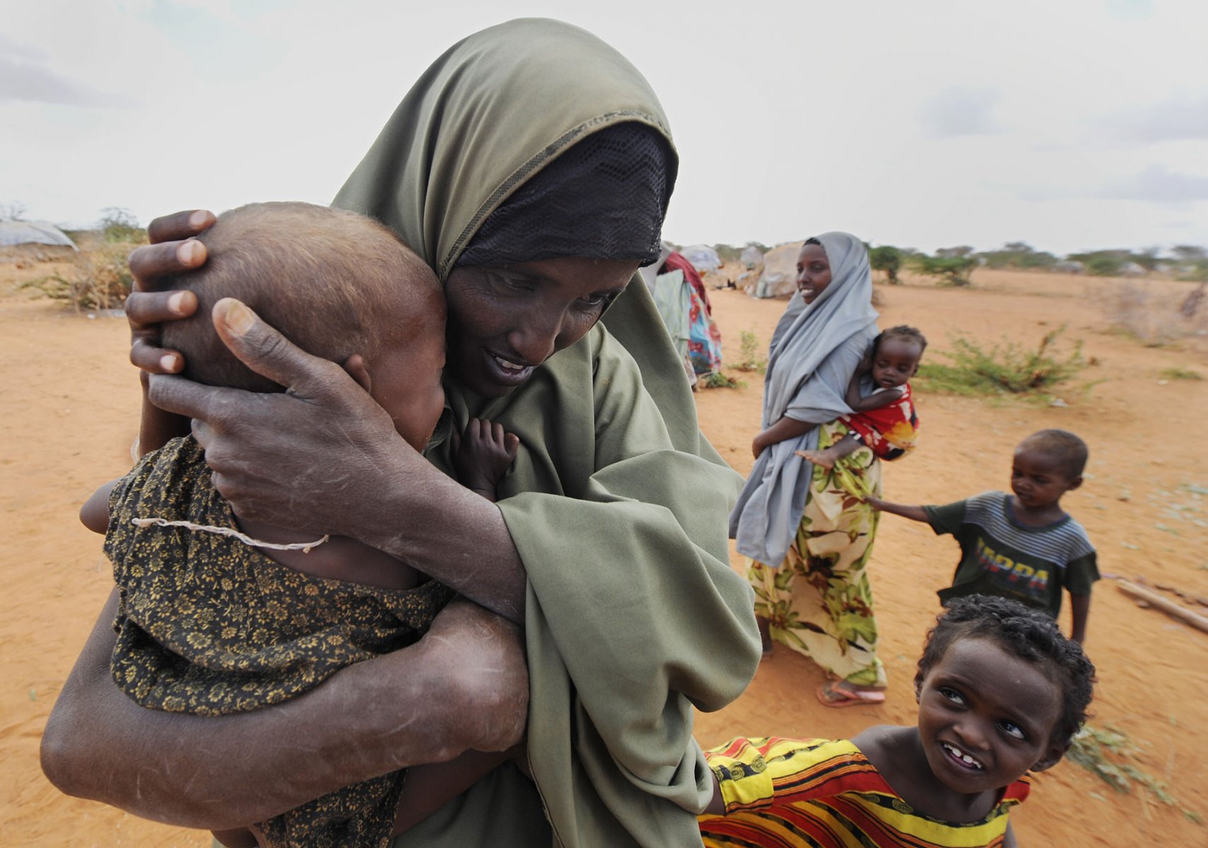 A somalian refugee cradles her little son at a refugee camp in Dadaab, northeastern Kenya on thursday, August 4, 2011 while another brother also tries to calm the toddler with his hand. Somalia and parts of Kenya have been struck by one of the worst draughts and famines in six decades, more than 350.000 refugees have found shelter in the worlds biggest refugee camp. Photo: Boris Roessler dpa  +++(c) dpa - Bildfunk+++