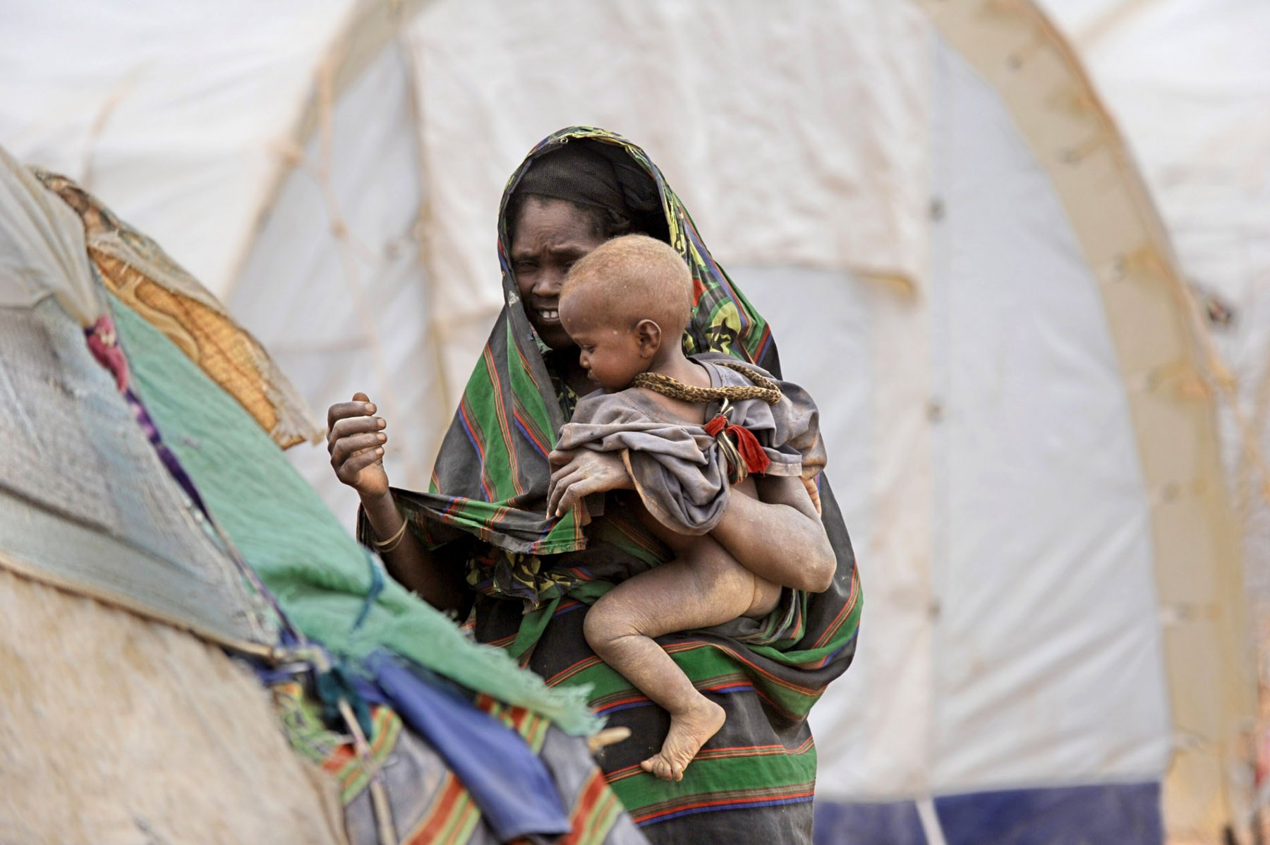 A Somalian woman and her son walking through a refugee camp in Dadaab, northeastern Kenya on thursday, August 4, 2011. Somalia and parts of Kenya have been struck by one of the worst draughts and famines in six decades, more than 350.000 refugees have found shelter in the worlds biggest refugee camp. Photo: Boris Roessler dpa  +++(c) dpa - Bildfunk+++