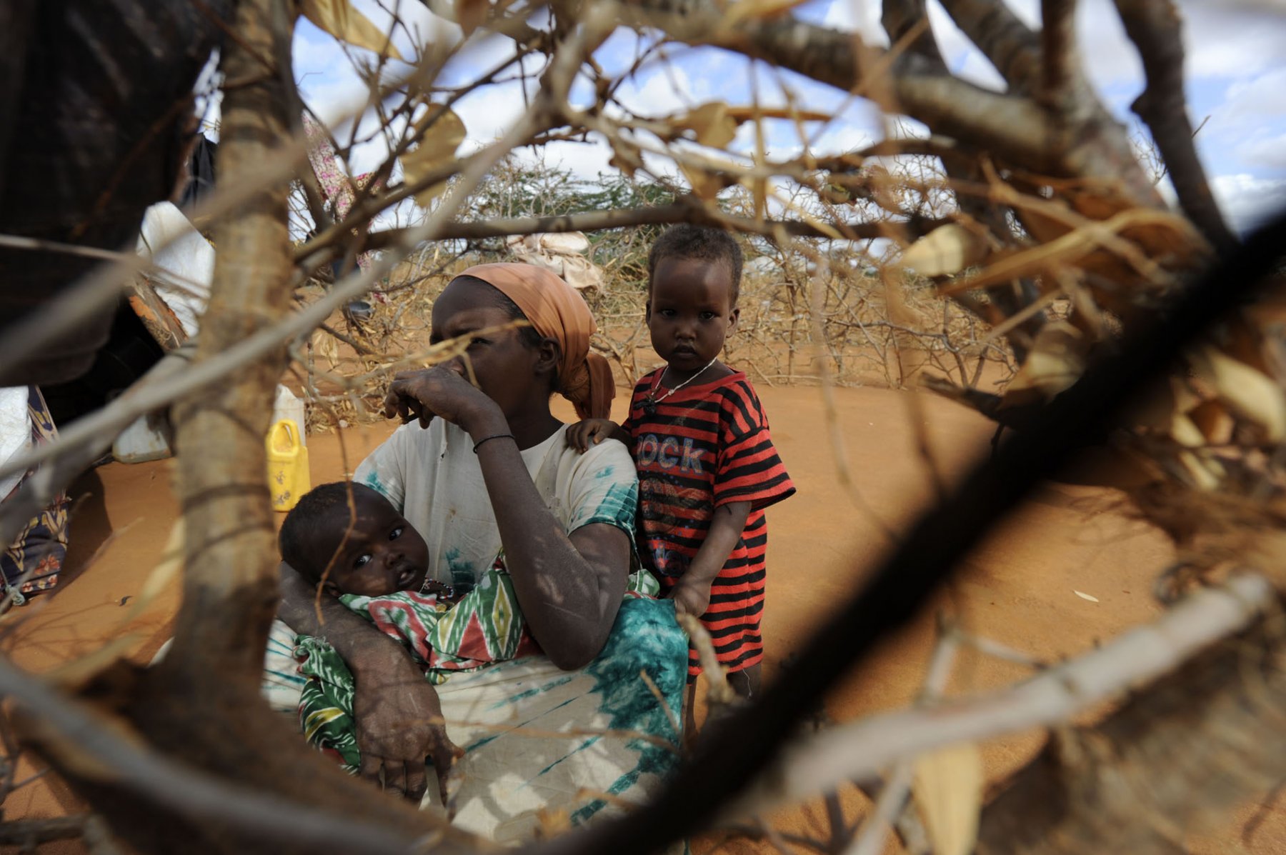 Set up to protect them from wild animals this woman and her children sit behind a fence made of firewood at a refugee camp in Dadaab, northeastern Kenya on thursday, August 4, 2011. Somalia and parts of Kenya have been struck by one of the worst draughts and famines in six decades, more than 350.000 refugees have found shelter in the worlds biggest refugee camp. Photo: Boris Roessler dpa  +++(c) dpa - Bildfunk+++