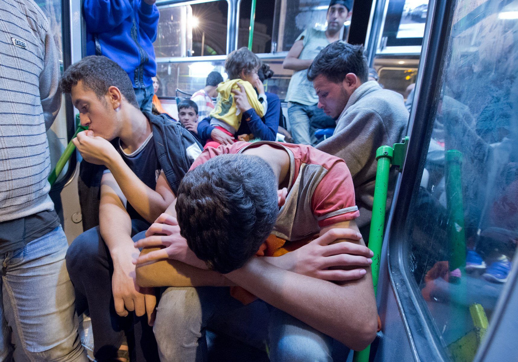 Mitten in der Nacht erreicht tausende Flüchtlinge im am 5. September 2015 vor dem Keleti-Bahmhof in Budapest die Nachricht, dass Sie nach Wochen der Ungewissheit Ungarn verlassen dürfen. Völlig erschöpft quetschen sich die Menschen in den Bussen zusammen. Foto: Boris Roessler/dpa