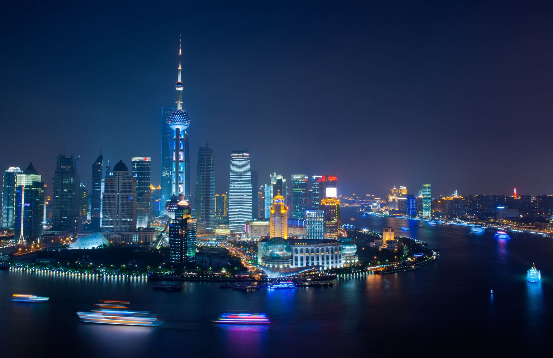 Bunt leuchten Ausflugsfähren, von denen aus die Passagiere einen Blick auf die illuminierte Skyline von Pudong werfen können. Foto: Boris Roessler