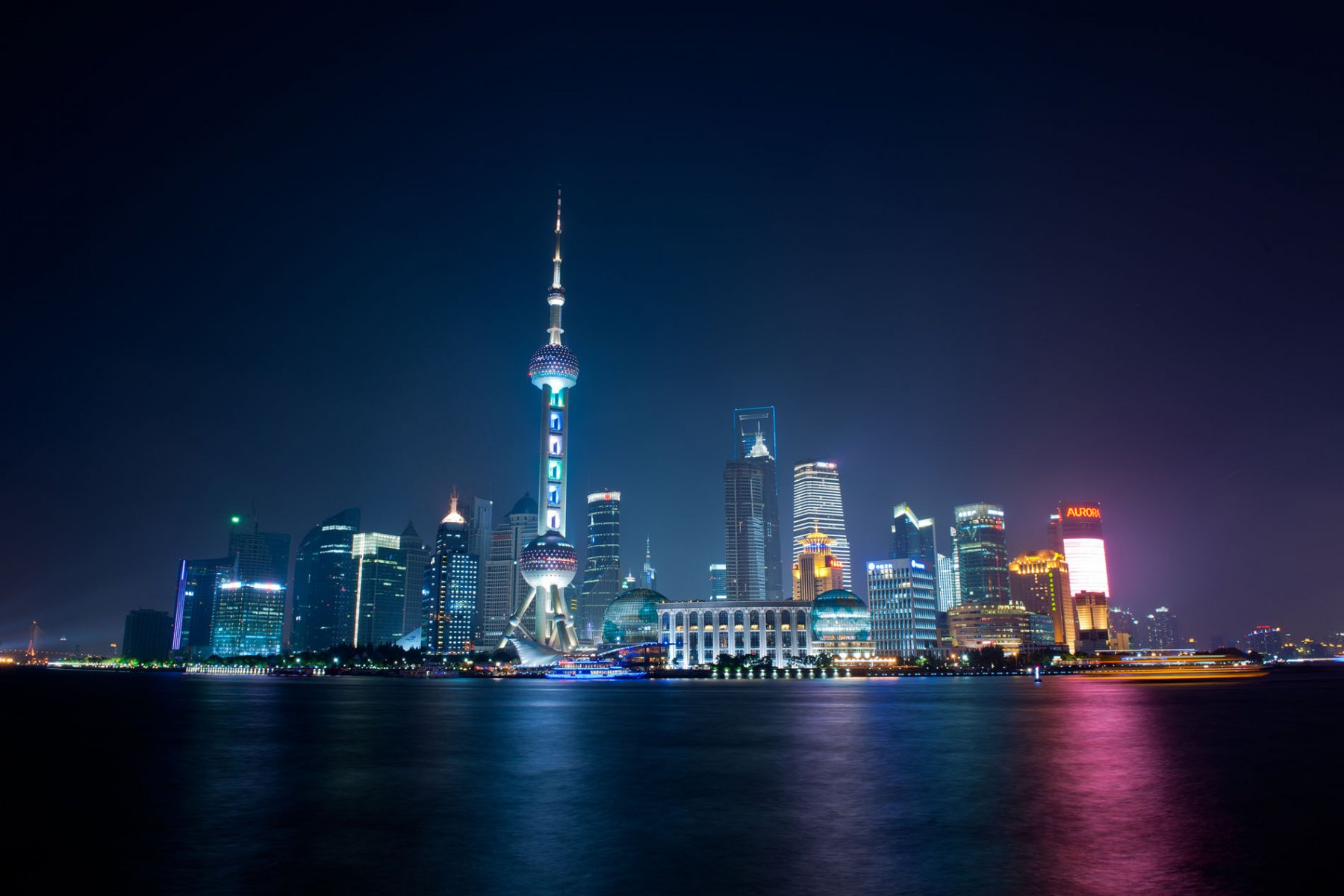 Bunt leuchten Ausflugsfähren, von denen aus die Passagiere einen Blick auf die illuminierte Skyline von Pudong werfen können. Foto: Boris Roessler