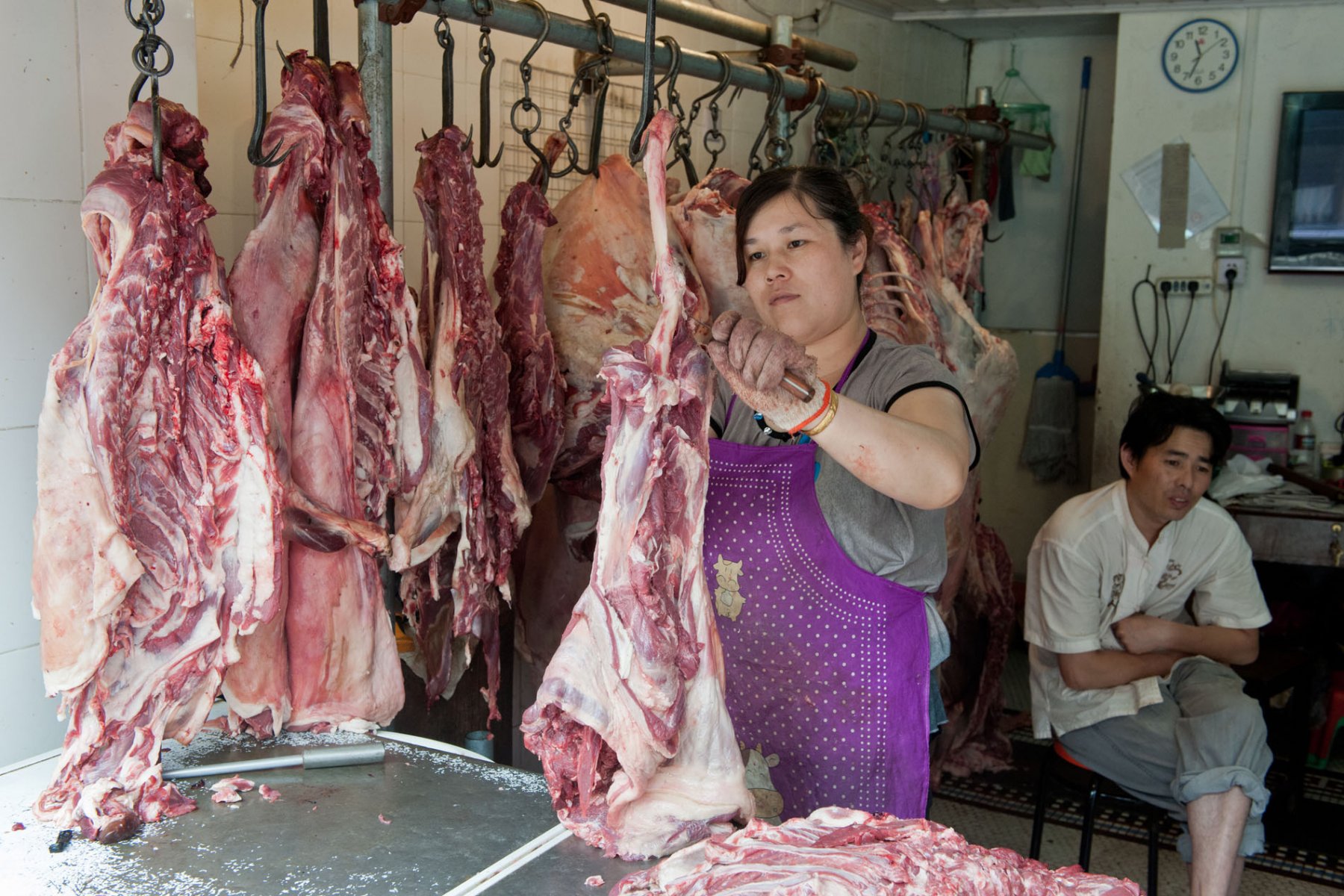 Schweinehälften zerlegt eine Verkäuferin auf ihrem Marktstand. Foto: Boris Roessler