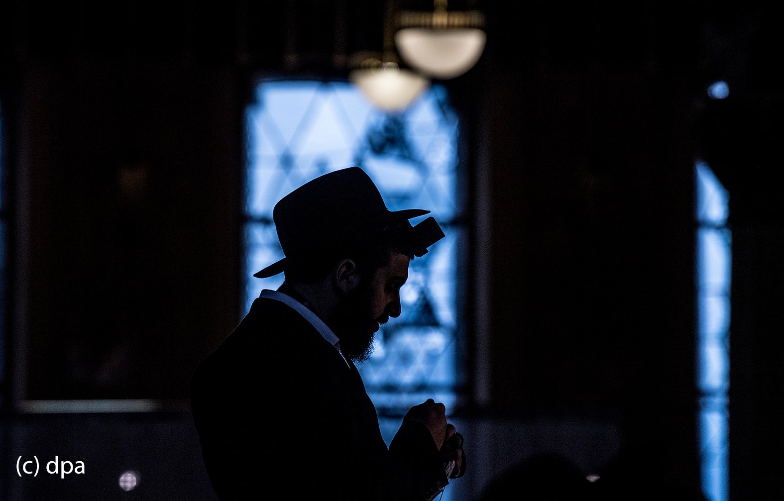 Nur als Silhouette zu erkenn ist ein gläubiger Jude, der in der Westend-Synagoge in Frankfurt am Main betet. In der Synagoge kommen die Gläubigen aus unterschiedlichen Glaubensausrichtungen bis zu dreimal täglich zum Gebet zusammen. 