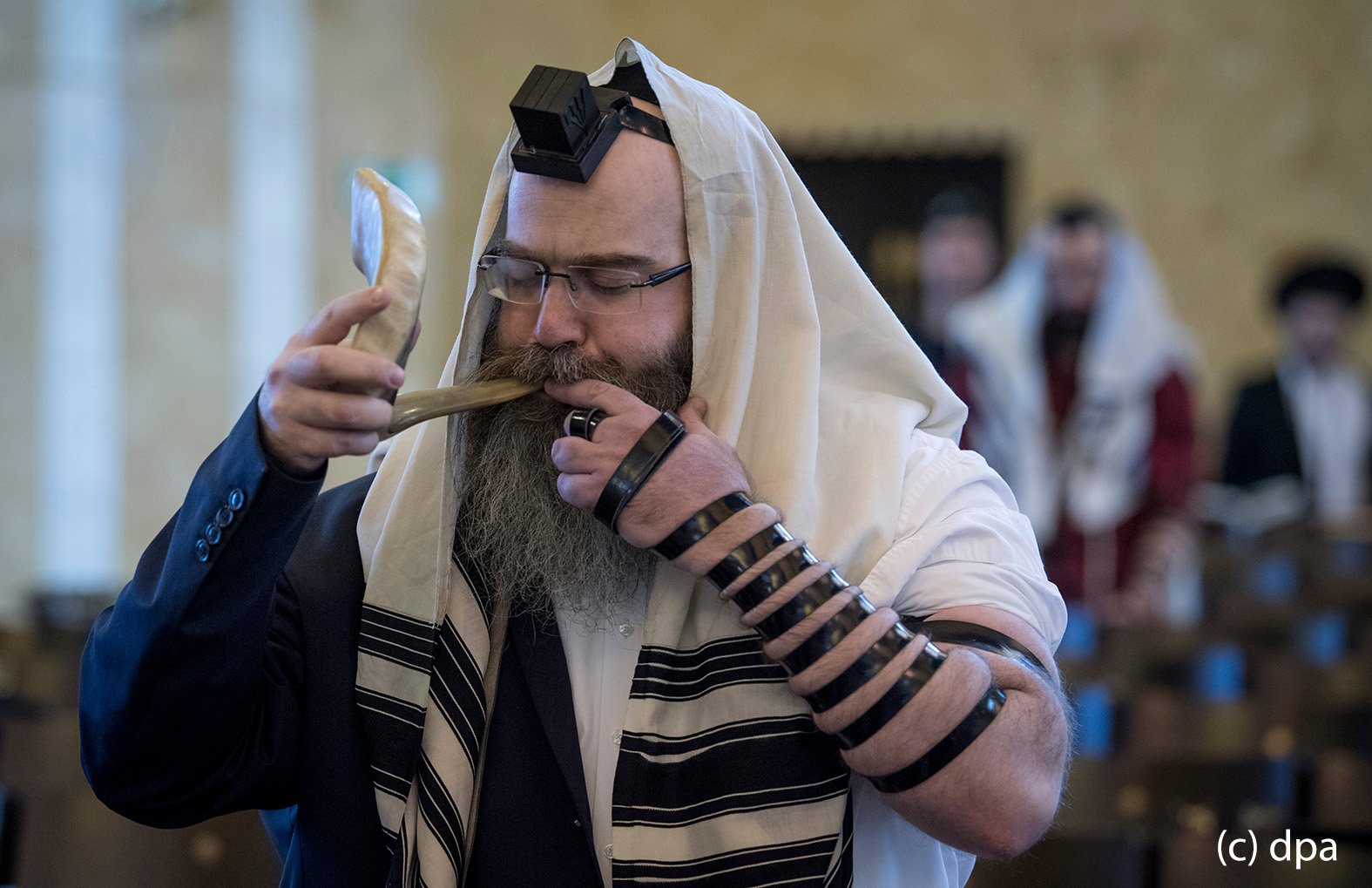 Während sei linker Arm mit einem Gebetsriemen aus Leder umwickelt ist, bläst ein gläubiger Jude in der Westend-Synagoge in Frankfurt am Main auf einem "Schofar", einem aus Widderhorn gefertigten Blasinstrument. 