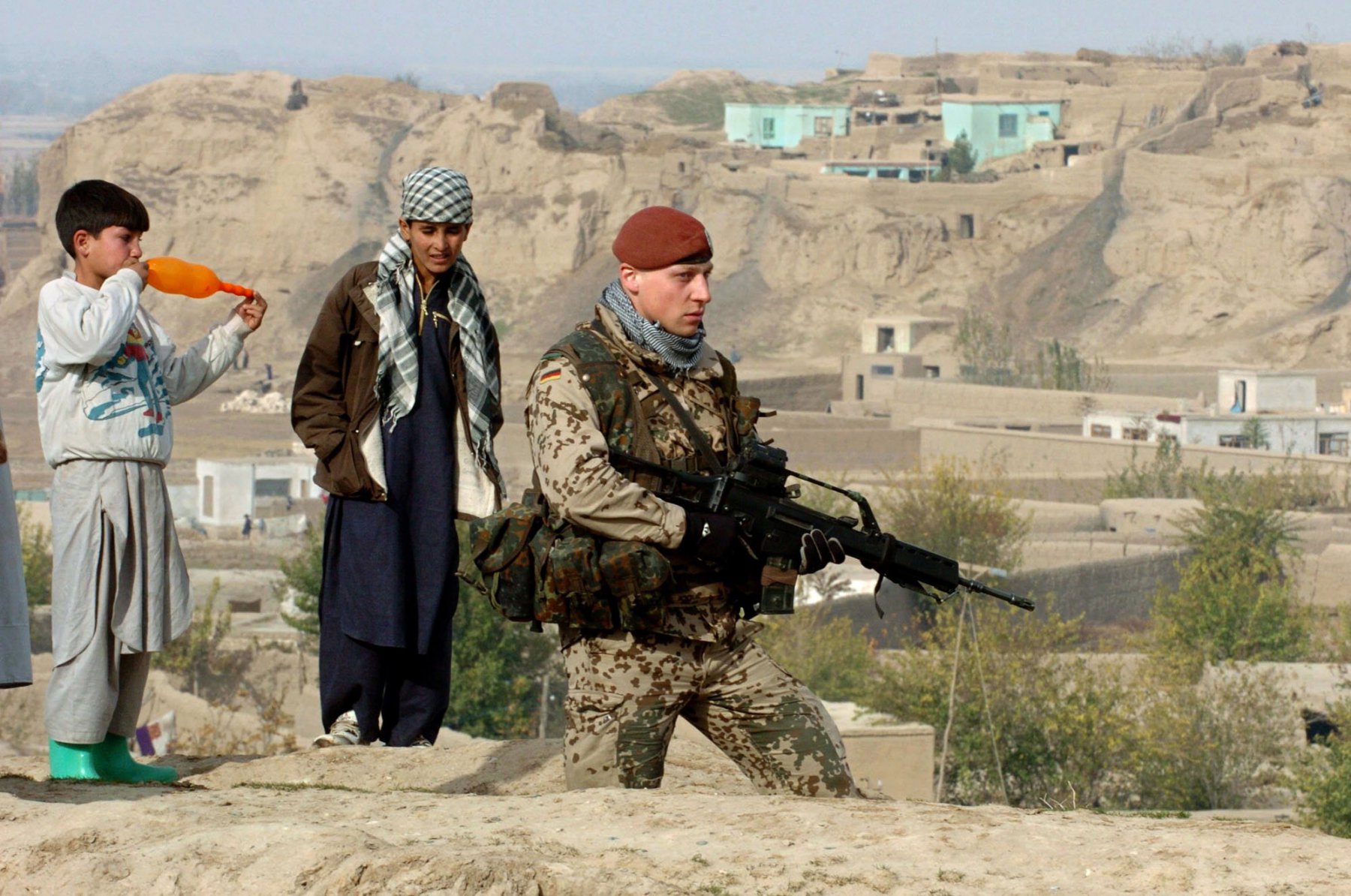 Von afghanischen Kindern beobachtet wird ein Bundeswehr-Soldat, der eine Anhöhe in der Nähe der Provinzstadt Kundus sichert. Foto: Boris Roessler/dpa