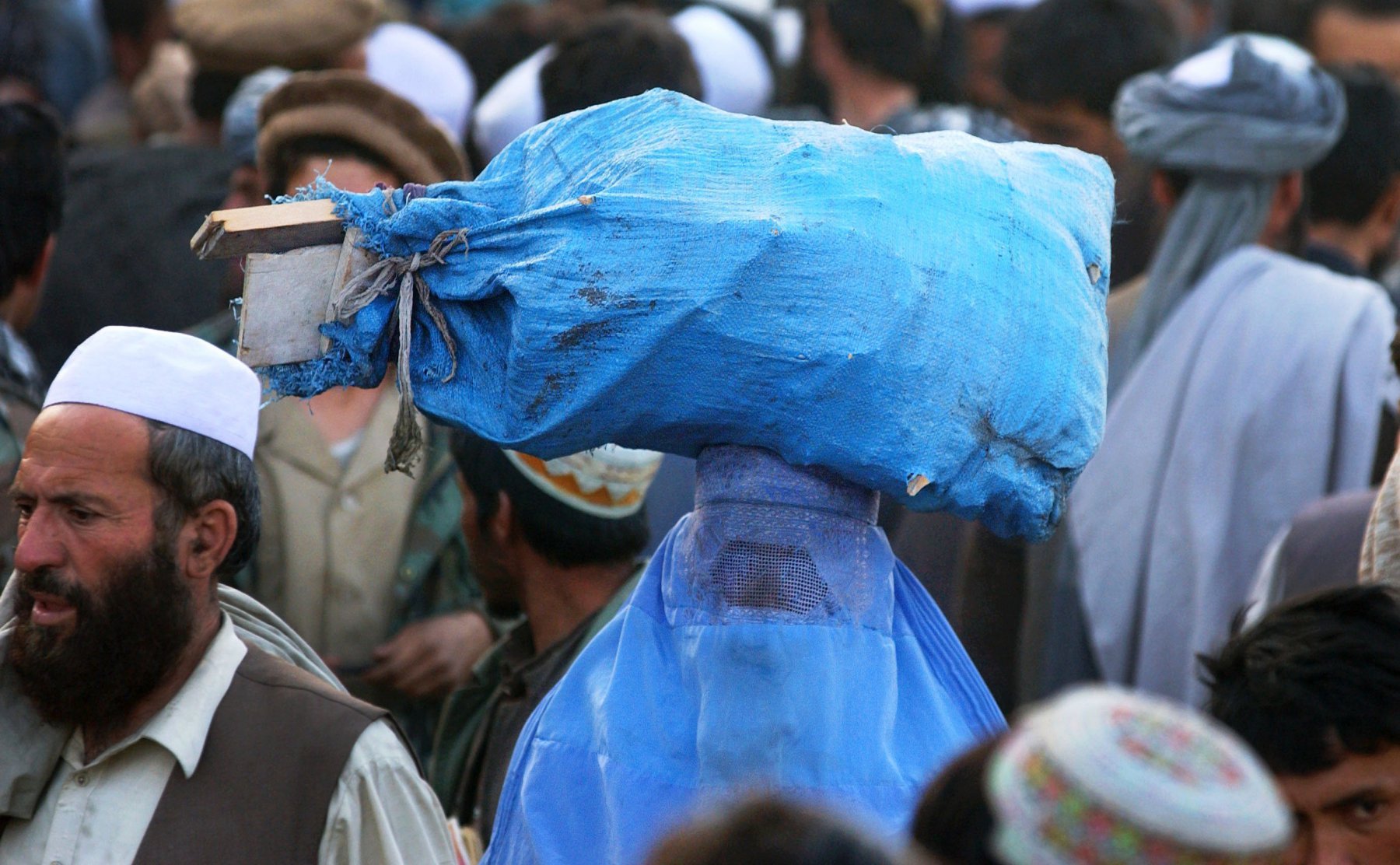 Brennholz transportiert eine verschleierte Frau über einen Basar der afghanischen Haupstadt Kabul. Im Gewimmel der Basare sind Männer eindeutig in der Überzahl. Foto: Boris Roessler/dpa