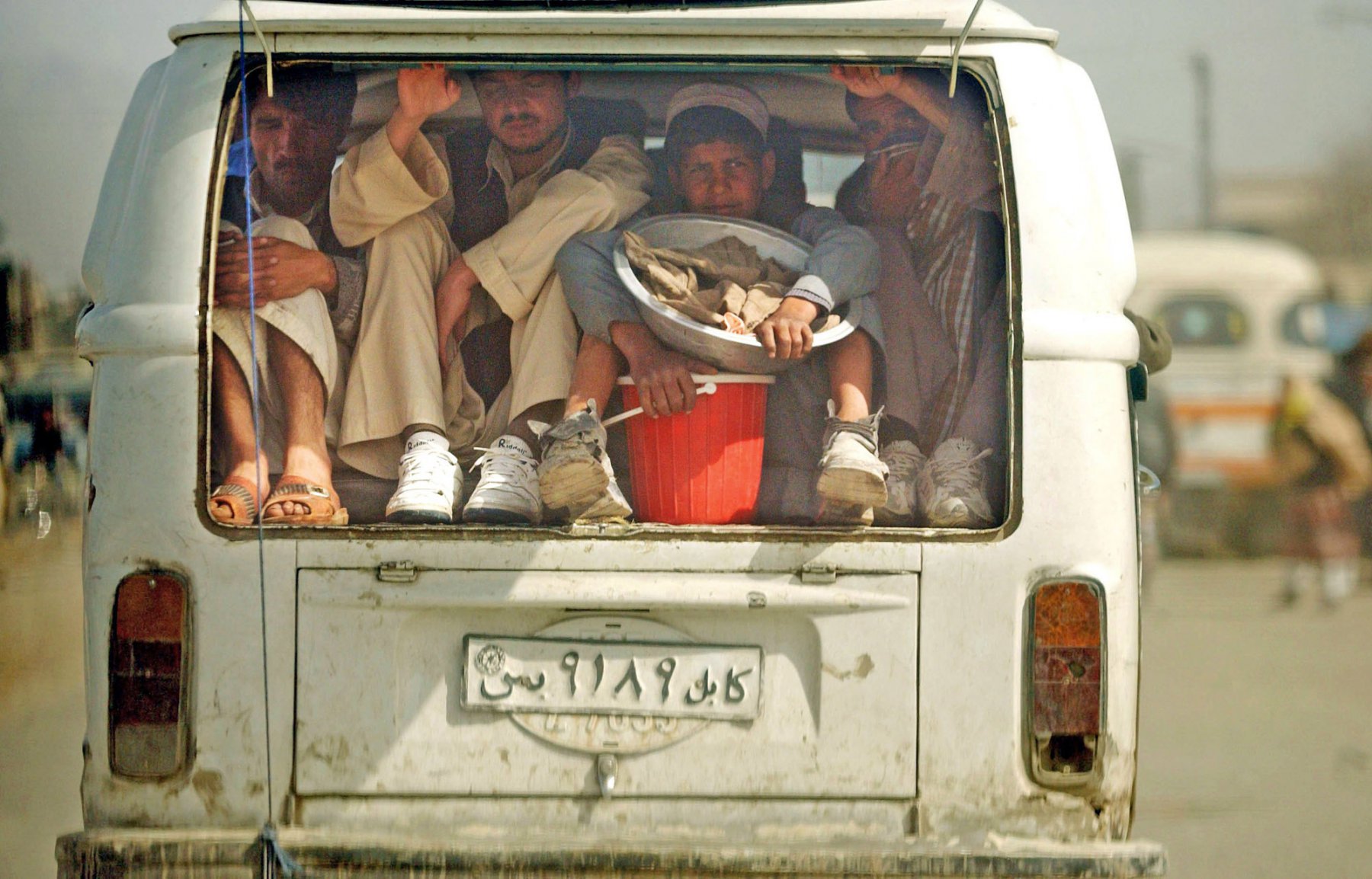 Zum Basar unterwegs sind diese vier Männer, die sich in Kabul auf die Ladefläche eines alten VW-Busses gequetscht haben. Aus Mangel an Privatwagen greifen die meisten Kabuli auf Taxis zurück oder schließen sich zu Fahrgemeinschaften zusammen. Foto: Boris Roessler/dpa