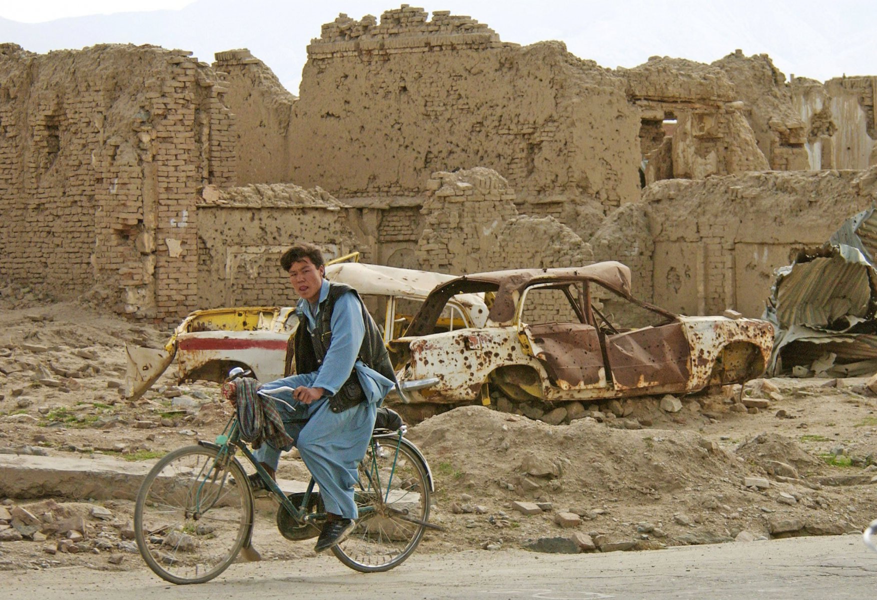 An Ruinen vorbei fährt ein junger Mann im Mazang-Viertel in der afghanischen Hauptstadt Kabul vorbei. Da sie sich keine Unterkunft leisten können, sind viele der jetzt aus Pakistan zurückkehrenden Flüchtlinge gezwungen, in den teilweise verminten Ruinen zu hausen. Foto: Boris Roessler/dpa