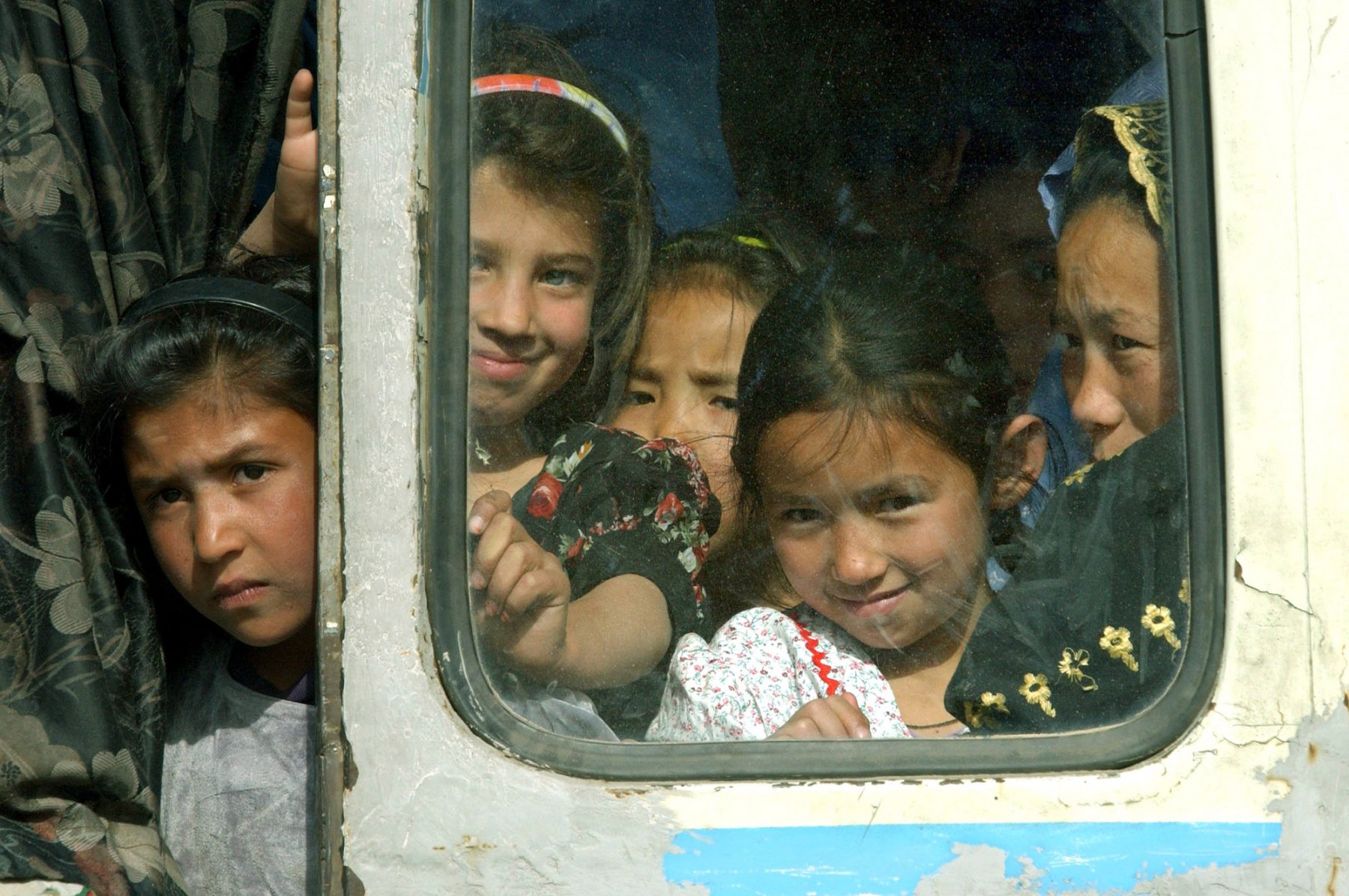 Noch etwas skeptisch blicken afghanische Mädchen aus einem hoffnungslos überfüllten Linienbus in der afghanischen Haupstadt Kabul. Busse zählen neben Taxis zu den Hauptverkehrsmitteln der Kabuler Bevölkerung. Foto: Boris Roessler/dpa