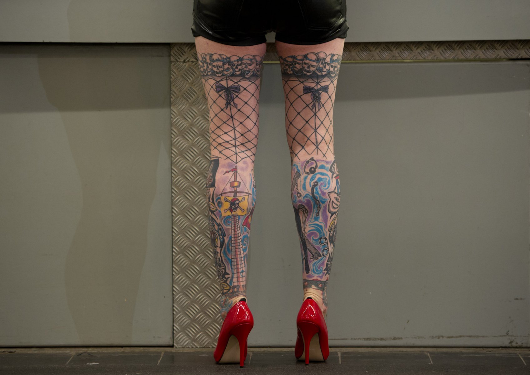 Lediglich tätowiert sind die Netzstrümpfe eines Mannes, der auf der Internationalen Tattoo-Convention in Frankfurt am Main in roten Pumps an der Garderobe steht. Foto: Boris Roessler/dpa 