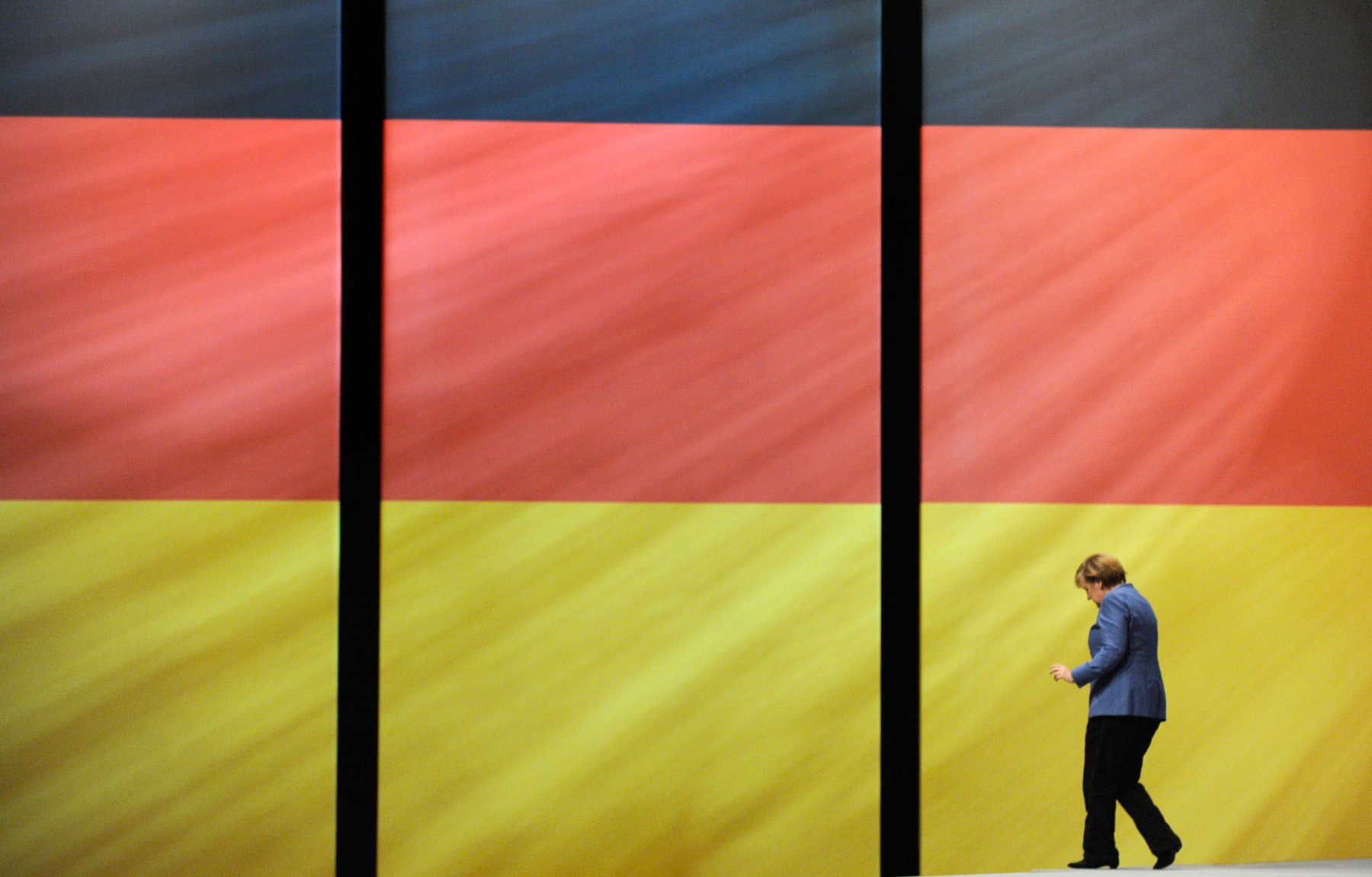 Bundeskanzlerin Angela Merkel geht auf einem Bundesparteitag der CDU vor einer riesigen Deutschlandfahne entlang. Foto: Boris Roessler/dpa