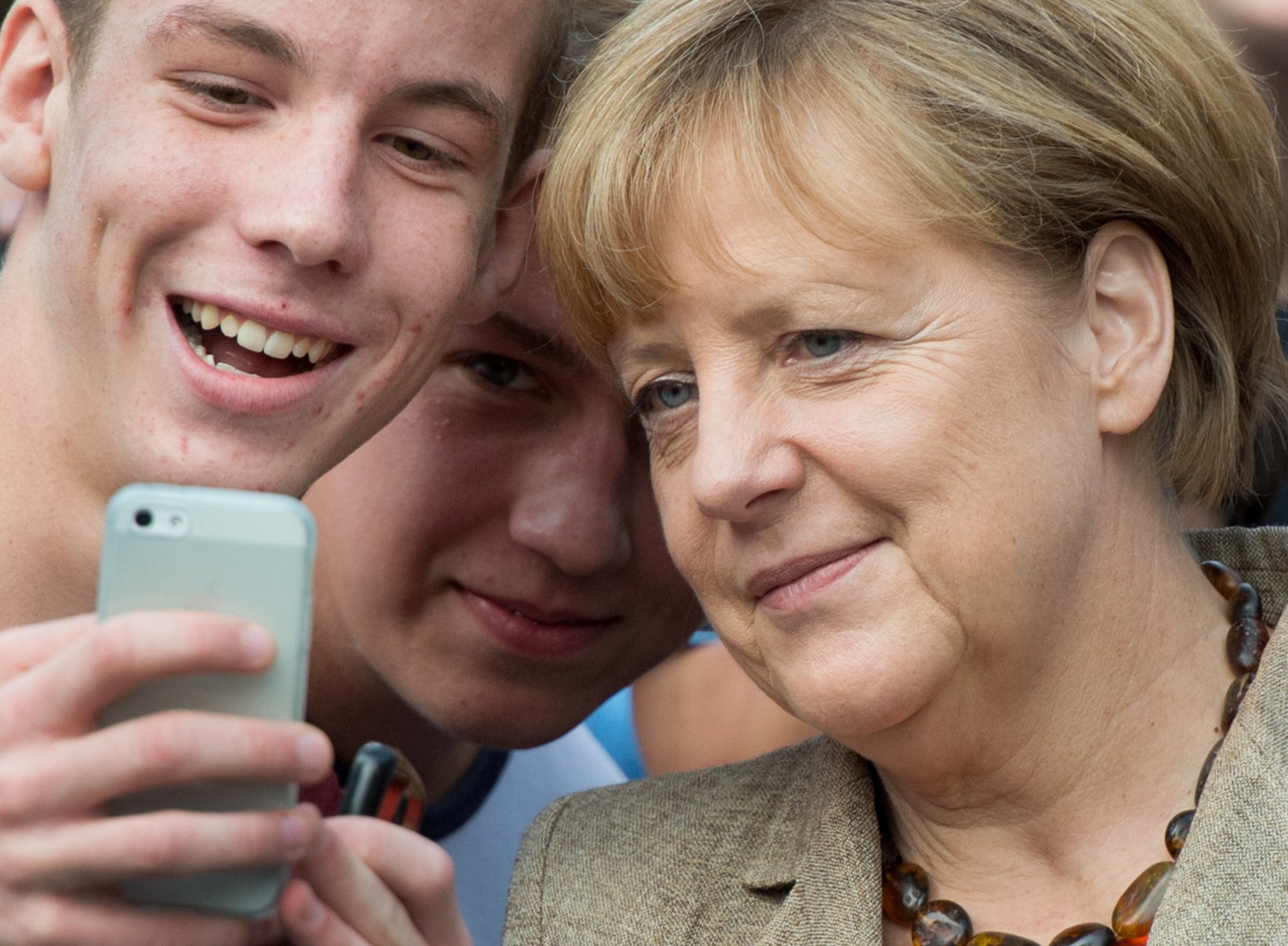 Bundeskanzlerin Angela Merkel posiert für "Selfies" mit Schülern in Groß-Gerau. Foto: Boris Roessler/dpa