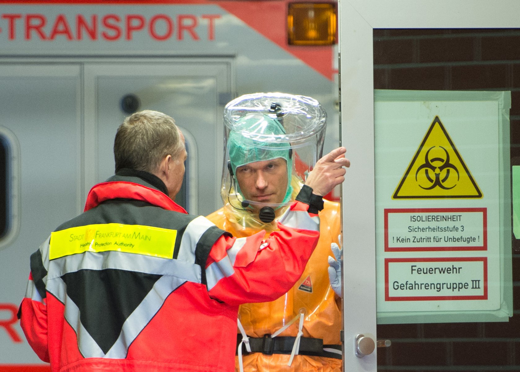 Ein an Ebola erkrankter Patient wird mit einem speziellen Krankenwagen zur Isolierstation der Uniklinik in Frankfurt am Main gebracht. Feuerwehrleute und Ärzte in Schutzanzügen begleiteten die Ankunft des Mannes. Foto: Boris Roessler/dpa 